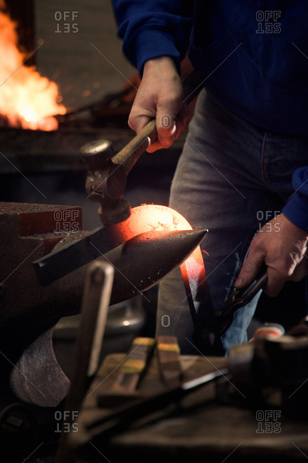 Farrier forging horseshoe on anvil