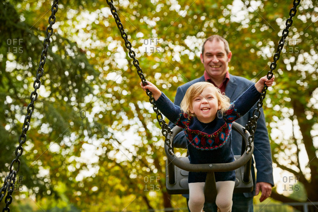 Father Pushing Daughter On Playground Swing Stock Photo Offset