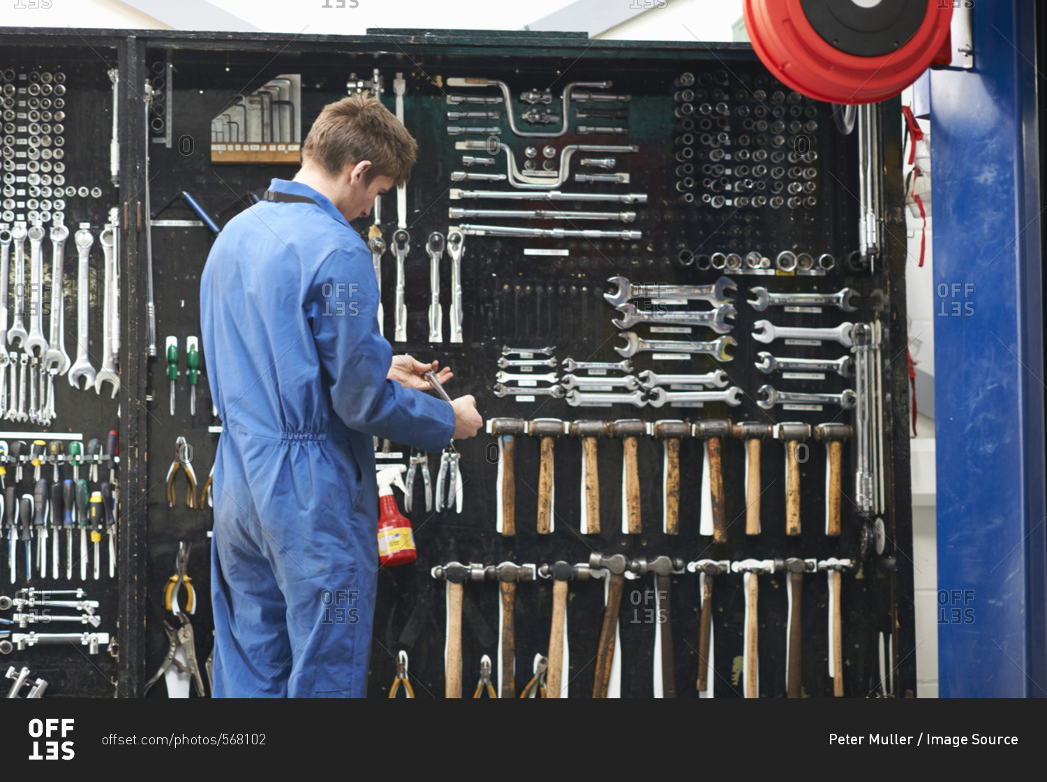 College mechanic student selecting wrench from repair garage tool kit