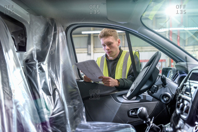 Apprentice vehicle inspector inspecting interior of vehicle in car factory