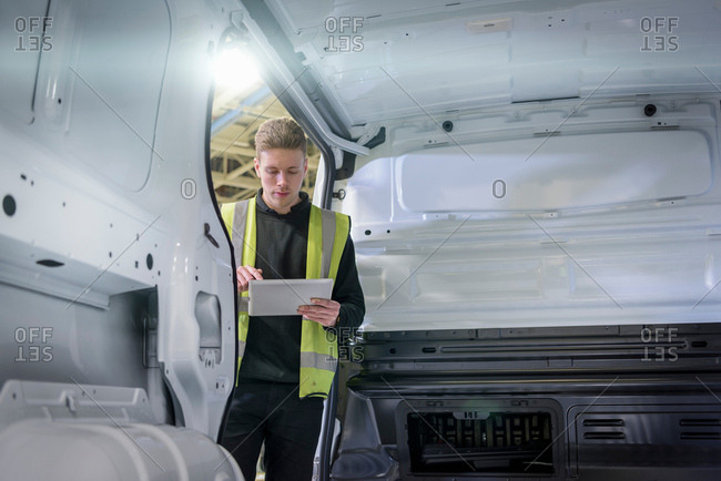 Apprentice vehicle inspector inspecting interior of vehicle in car factory