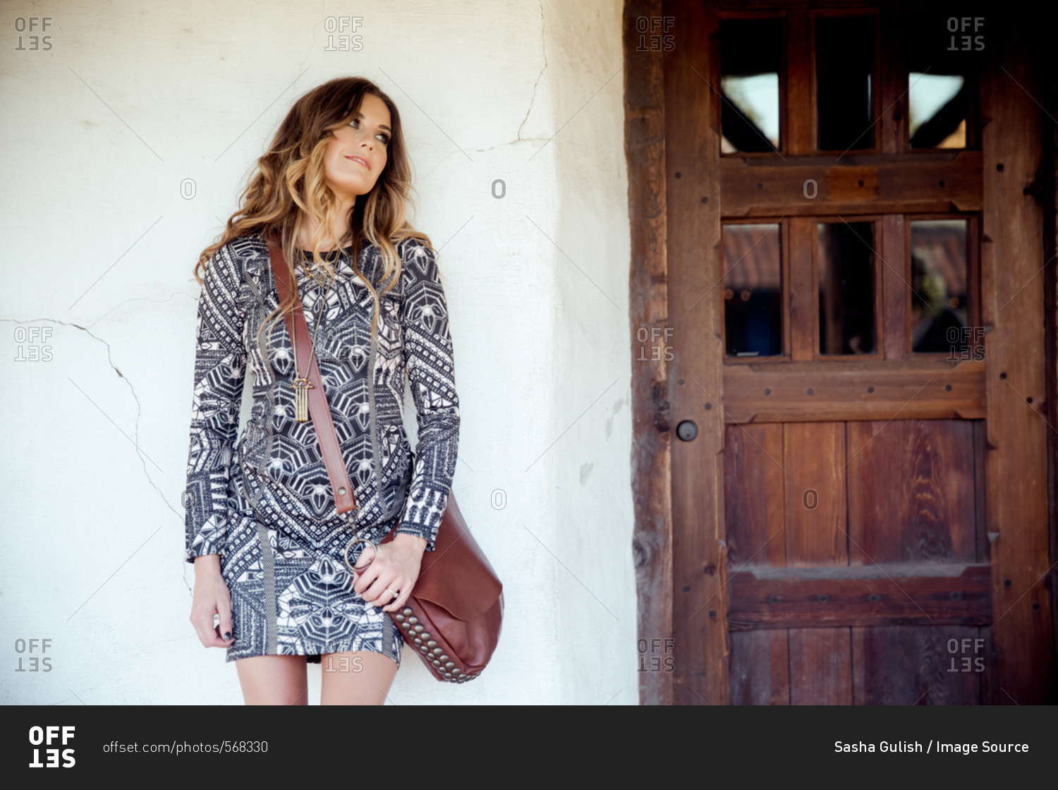 Stylish young woman looking over her shoulder from front door