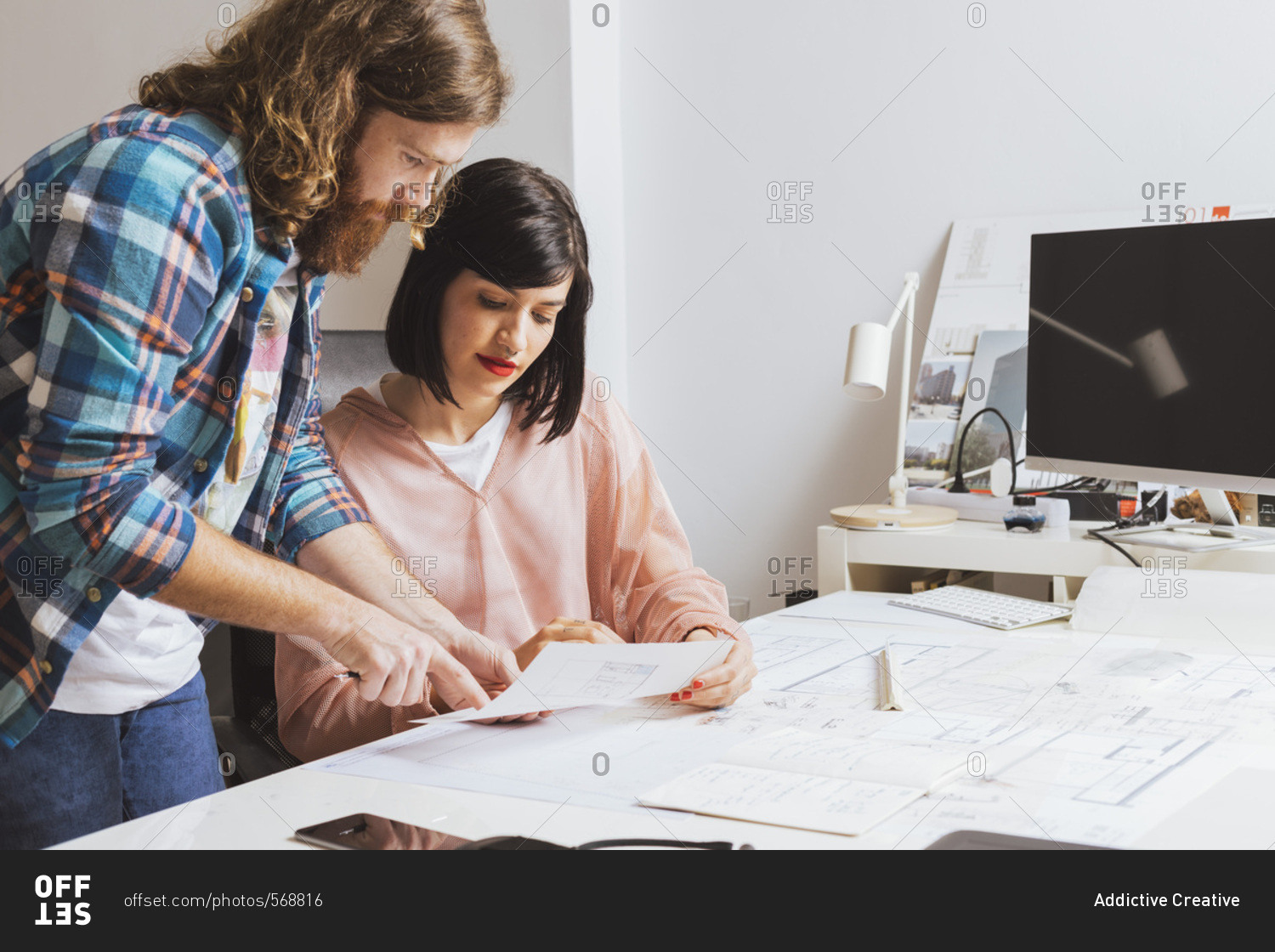 Two designers in the office talking about the blueprint during the teamwork.