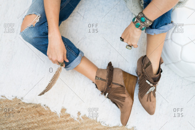 From above crop shot of trendy female in jeans and stylish boots wearing accessories.