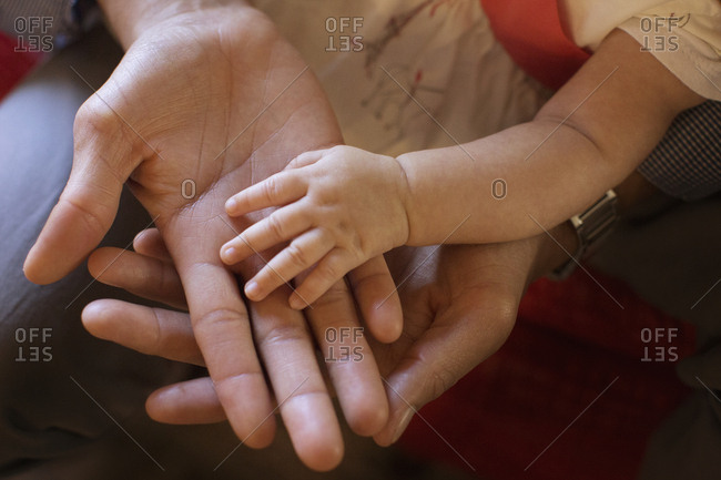 Baby's hand on top of father's hands
