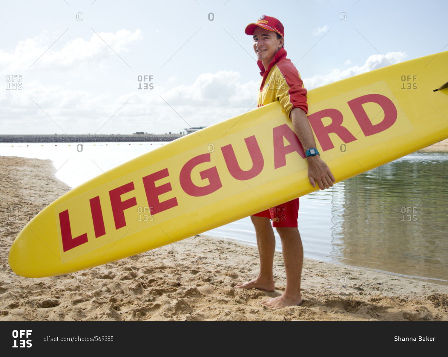 Lifeguard holding a surfboard standing on the beach in Darwin, Australia