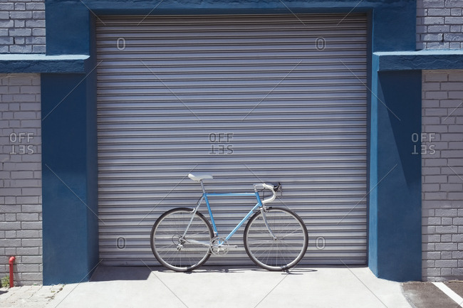 Vintage bicycle parked by closed workshop during sunny day