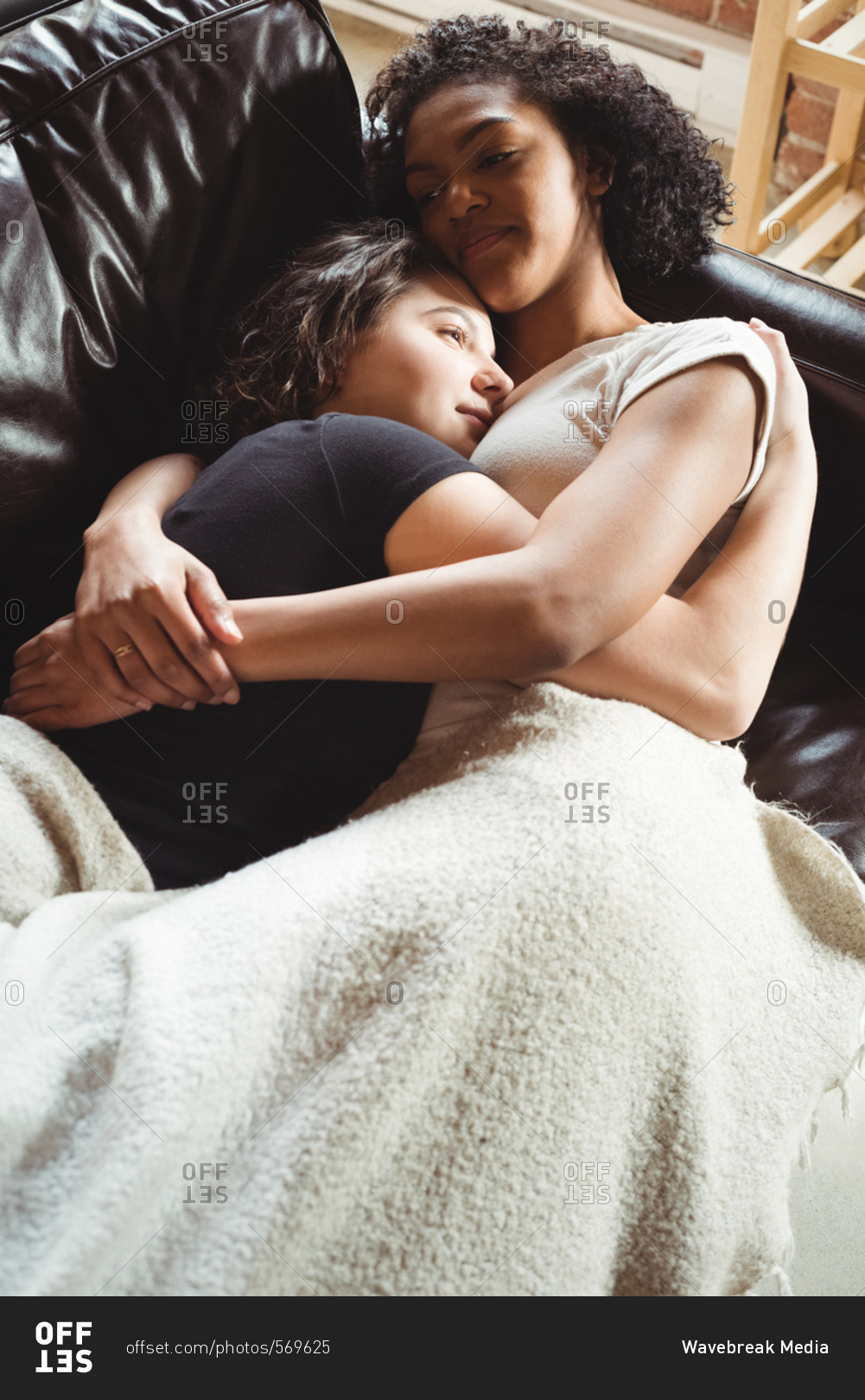 Lesbian couple sleeping together on couch at home stock photo - OFFSET