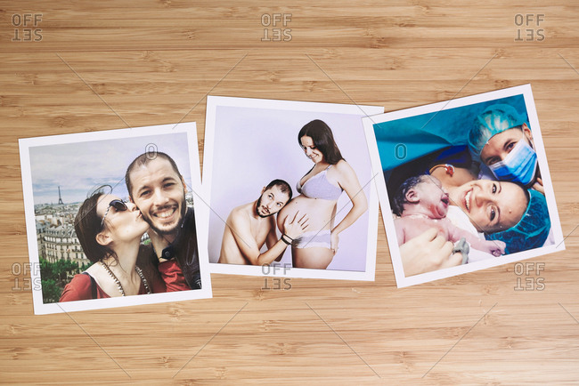 Arrangement of three family pictures of pregnancy and delivery on a bamboo wooden table