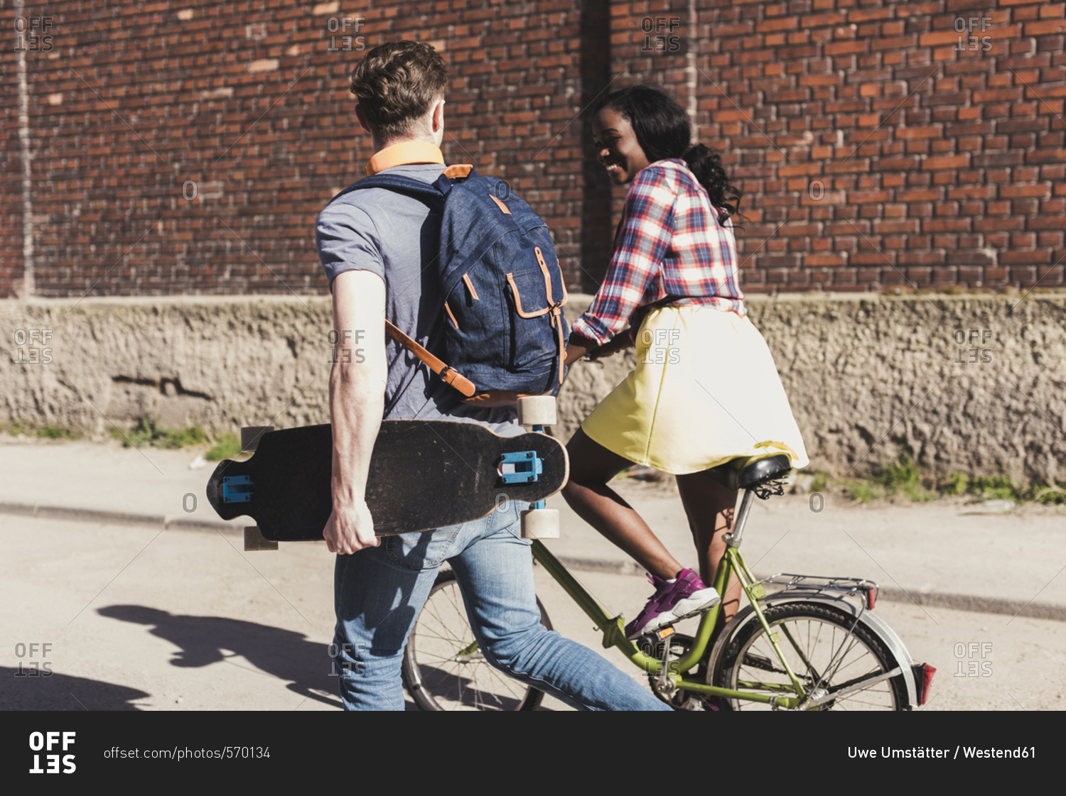 Young couple with bicycle and skateboard walking in the street