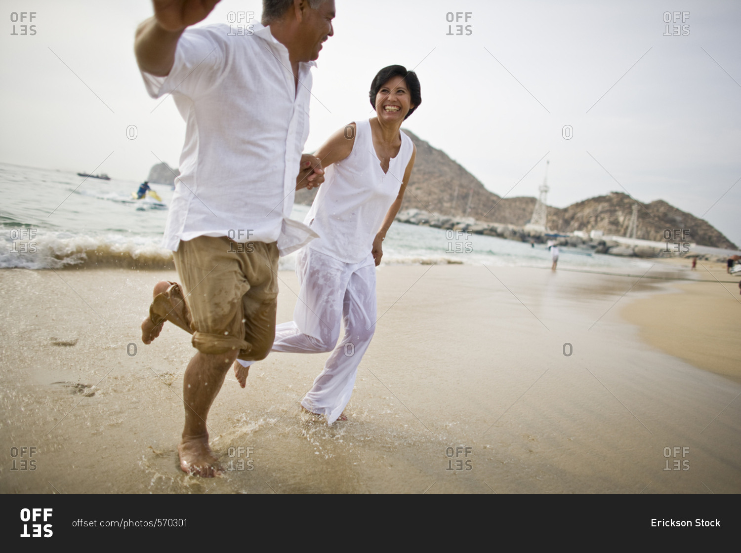 Middle-aged couple running while holding hands on a beach