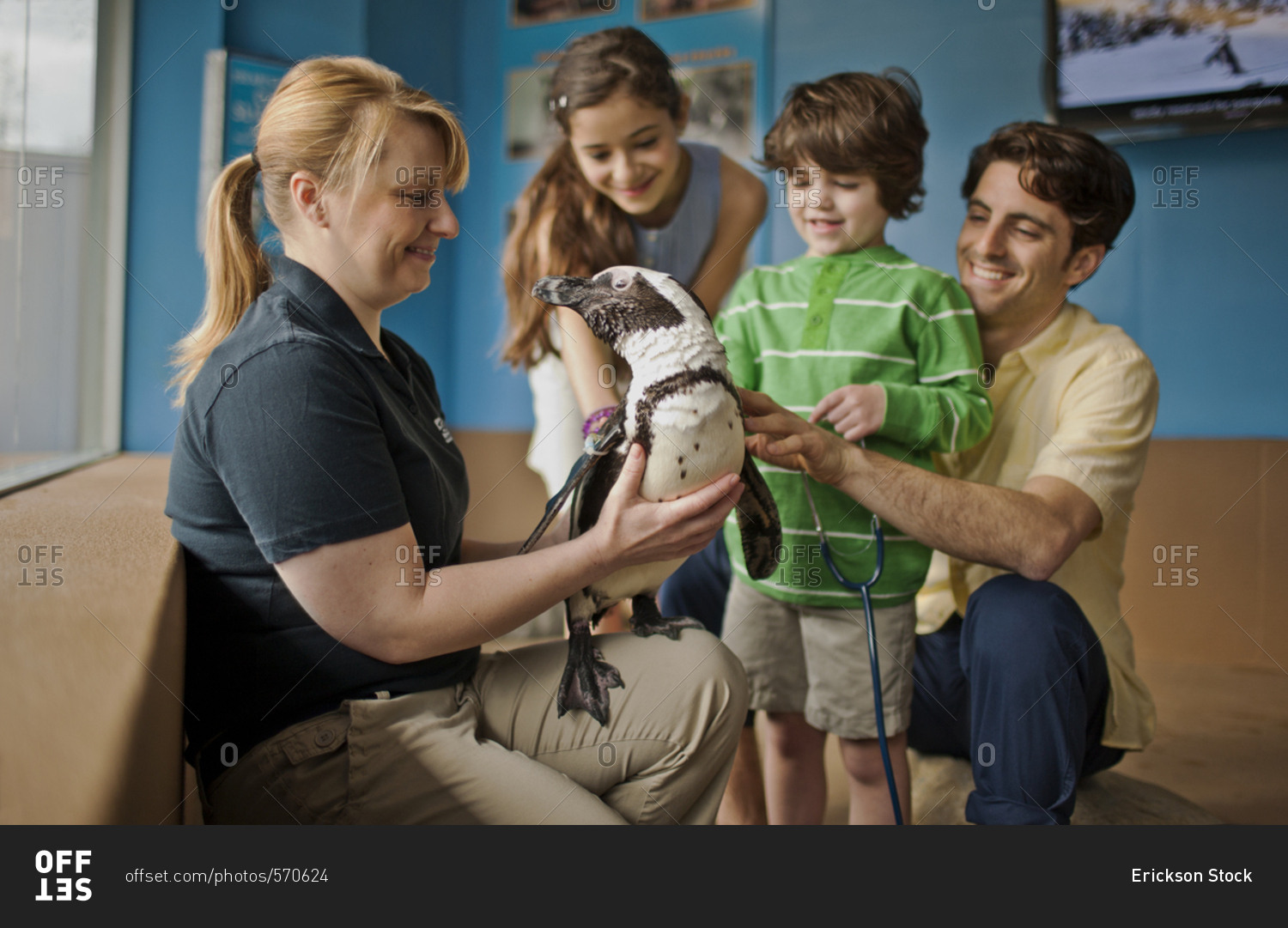 Zoo keeper showing a penguin to a family