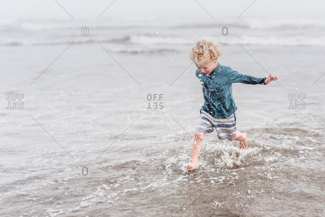 Boy running and splashing in ocean waves