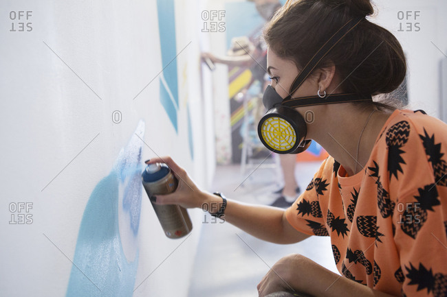 Graffiti artist spray painting wall at studio