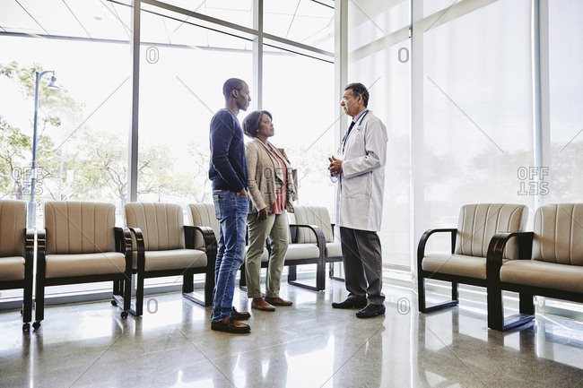 Doctor discussing with patients in waiting room at medical clinic