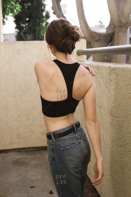Brunette woman wearing sports bra and jeans looking away
