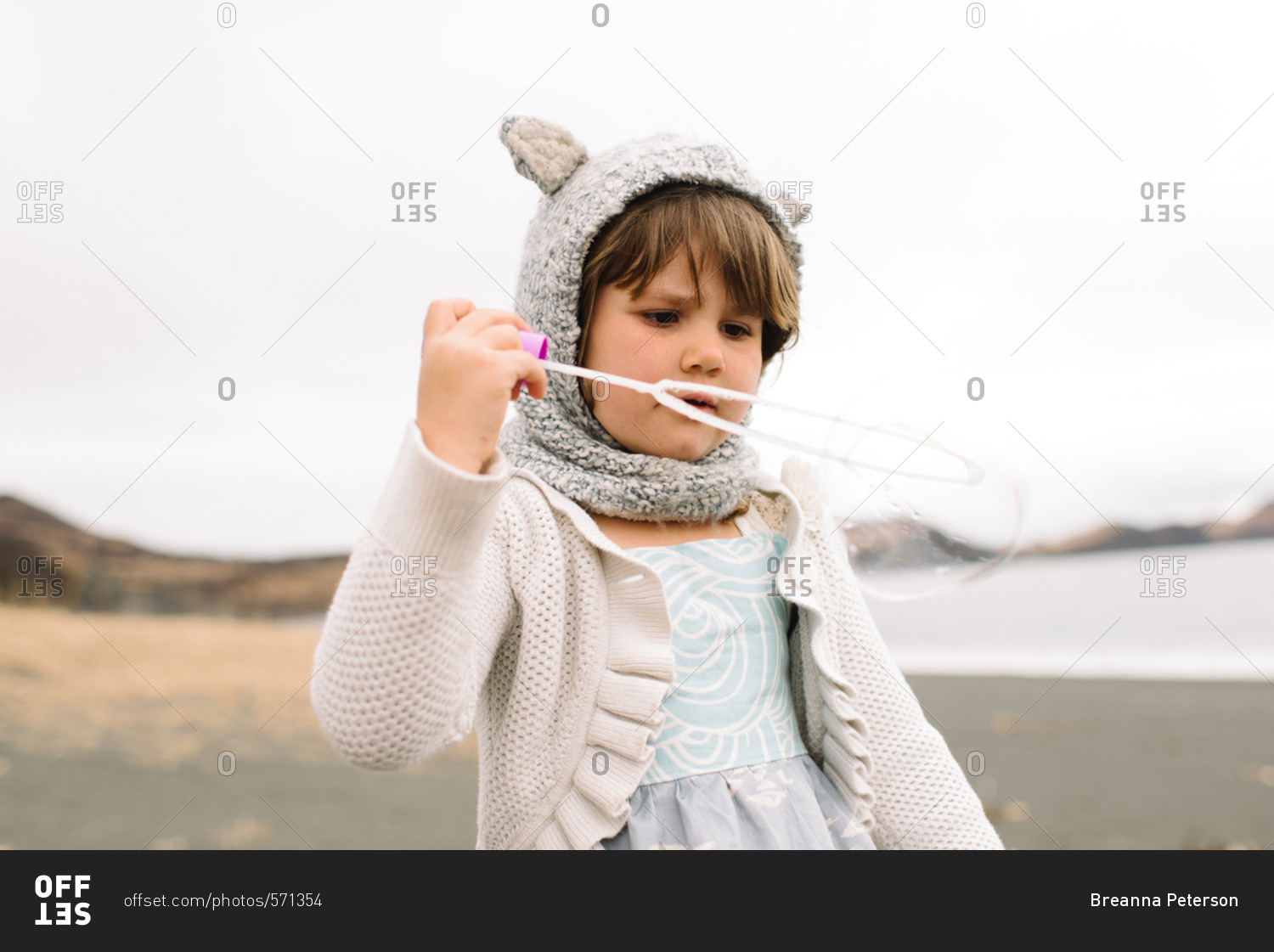 Little girl in knit hat with ears blowing bubbles