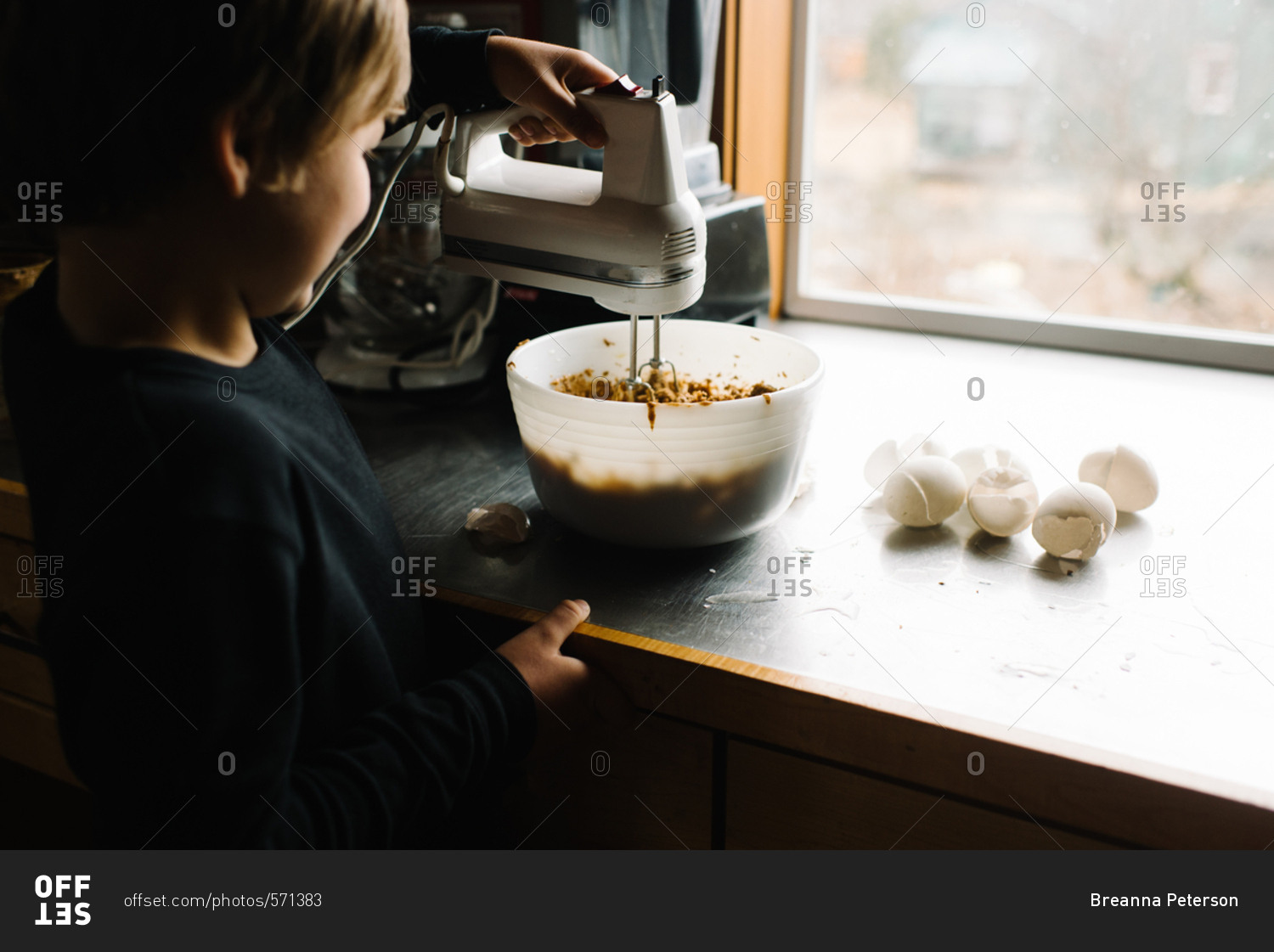 Child using a hand mixer to blend batter in bowl