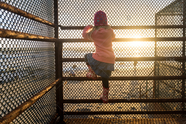 Girl climbing on a beach access railing at sunset