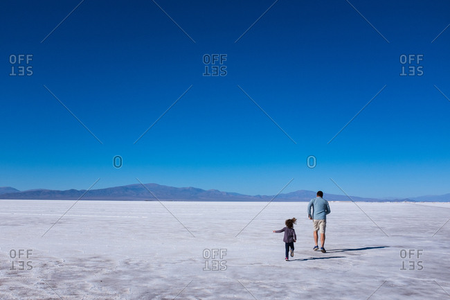 Father and daughter running through salt flats