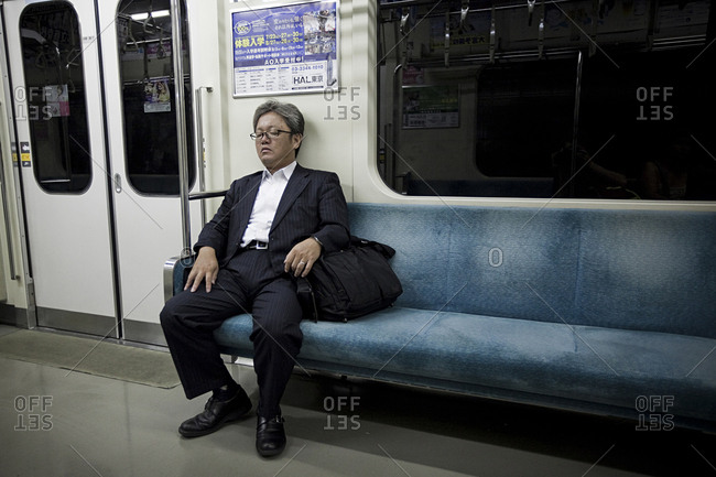 Tokyo, Japan - July 12, 2011: A business man is taking a rest in a metro train in Tokyo.