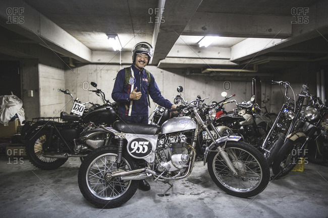 Tokyo, Japan - May 18, 2016: Japanese man giving a thumbs up in a garage full of motorcycles.