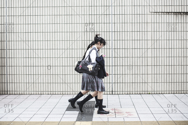 Tokyo, Japan - May 16, 2016: Two Japanese school girls walking on a street in Tokyo.