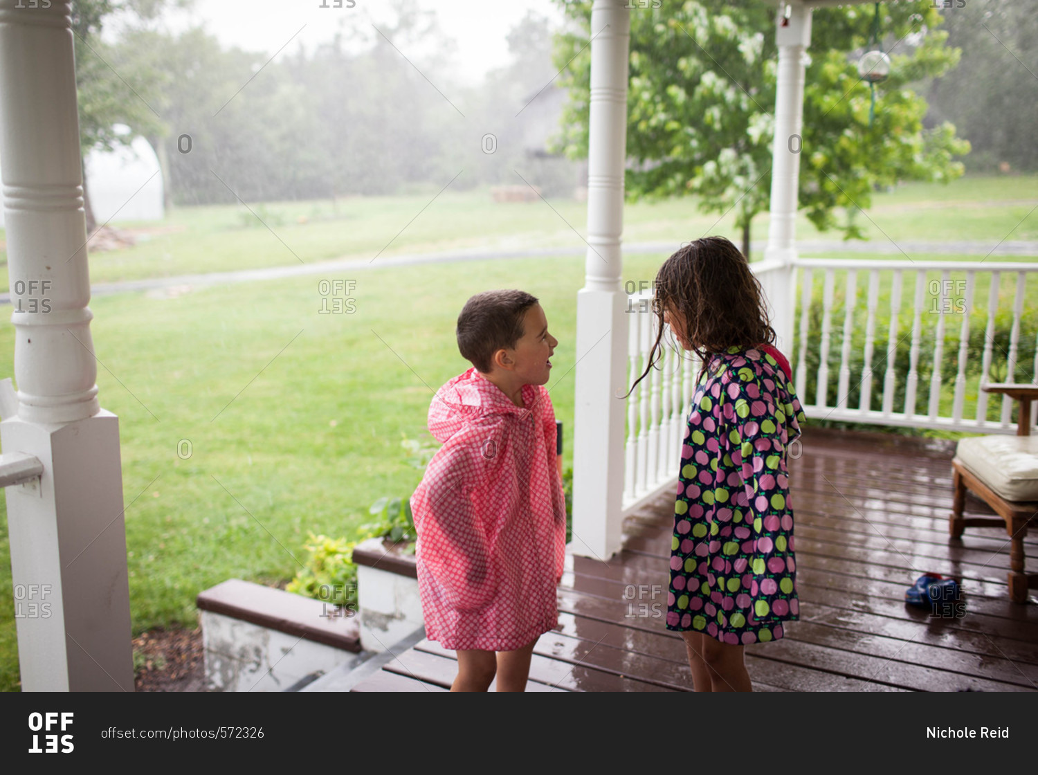 Wet kids on porch in rain coats