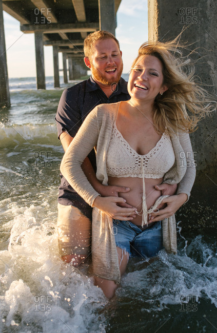 Pregnant couple under sea pier