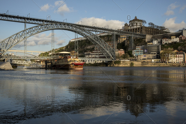 Porto, Portugal - April 23, 2016: River boat crossing the Douro under the Dom Luis bridge at dusk