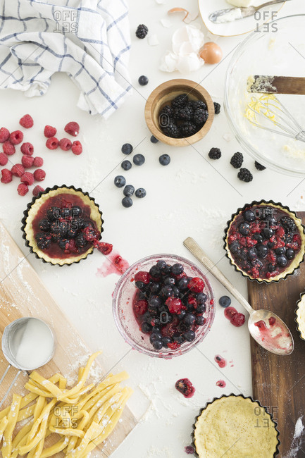 Ingredients for making tarts with freshly prepared mixed berries in tart tins