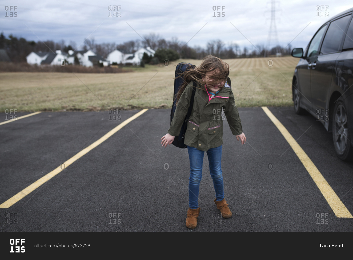 Little girl in a parking lot with her wind blowing in her face