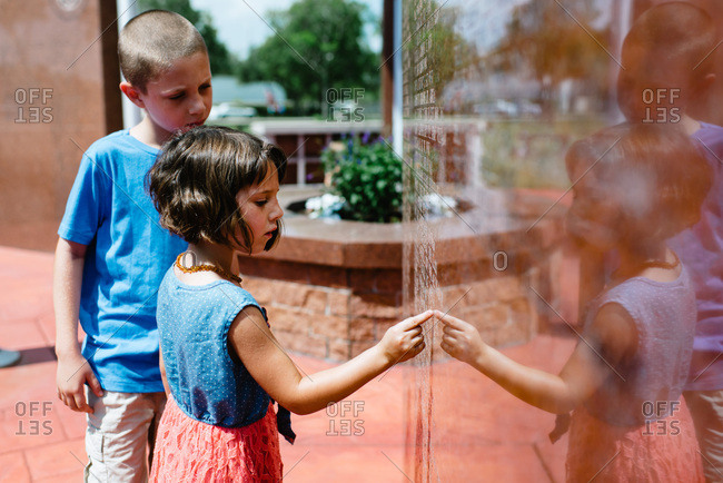 Children touching names on a Veterans' Memorial statue.