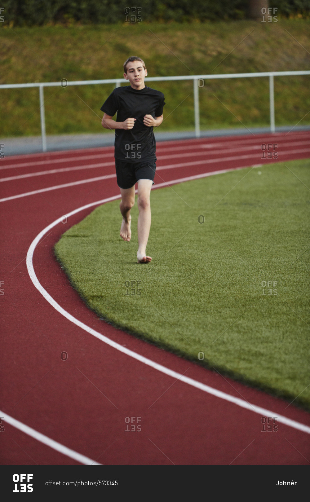 Teenage boy running next to sports track