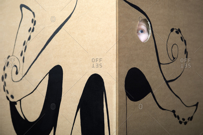 Girl peeking out of cardboard box painted with an octopus