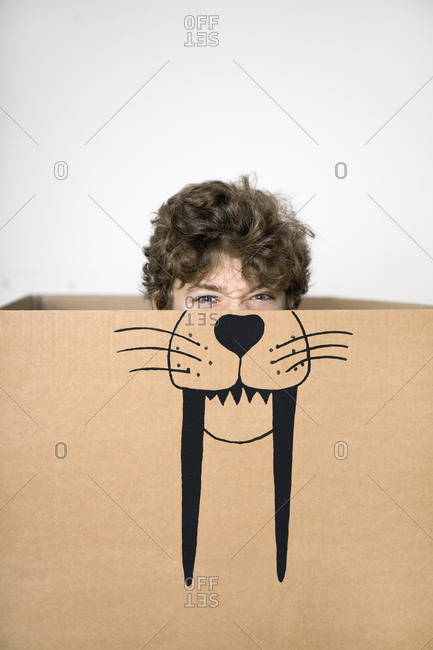 Boy inside a cardboard box painted with a saber-toothed tiger