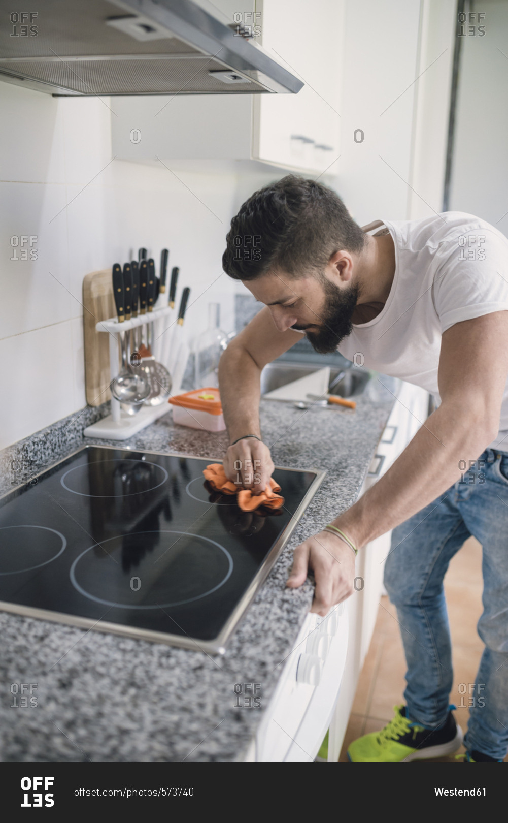 Young man cleaning ceramic hob