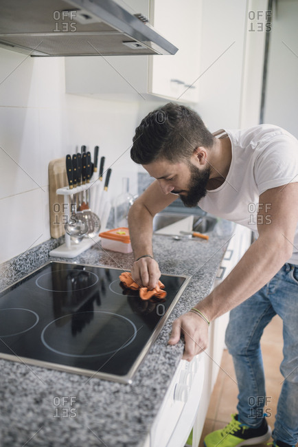 Young man cleaning ceramic hob