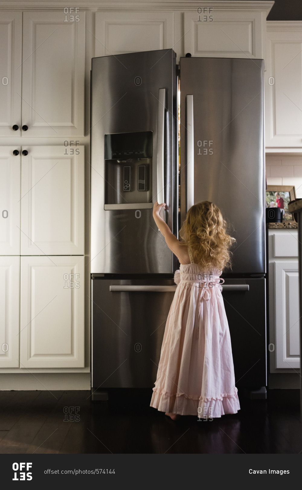 Rear view of girl opening refrigerator at home