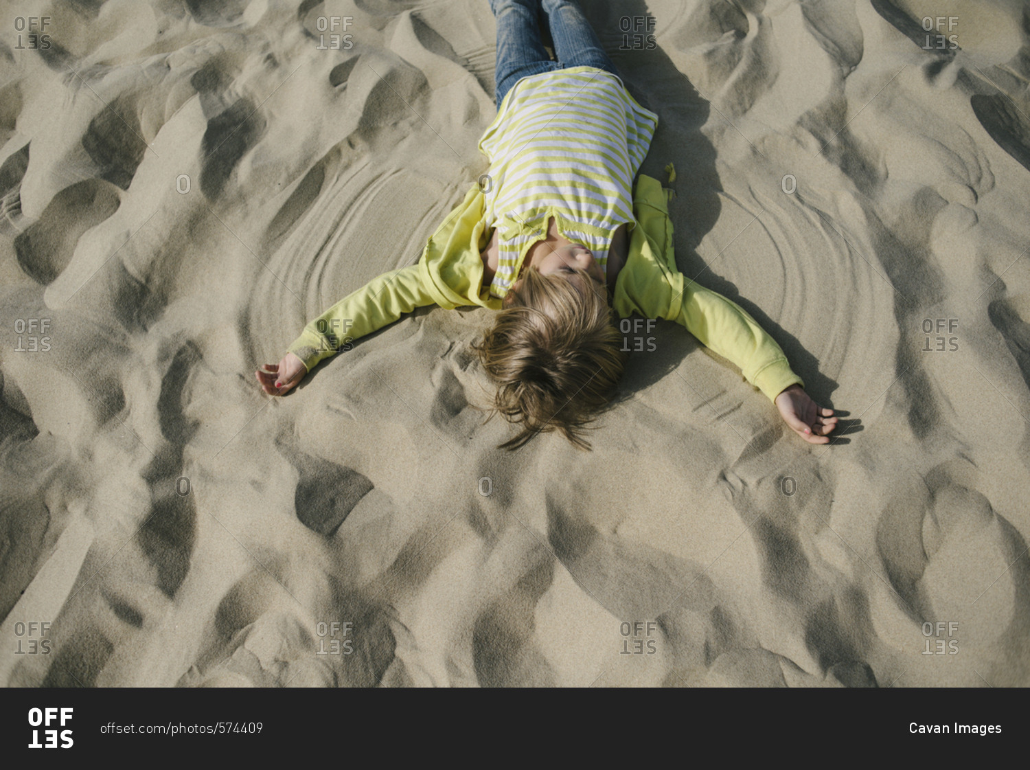 Overhead view of girl making sand angel at beach