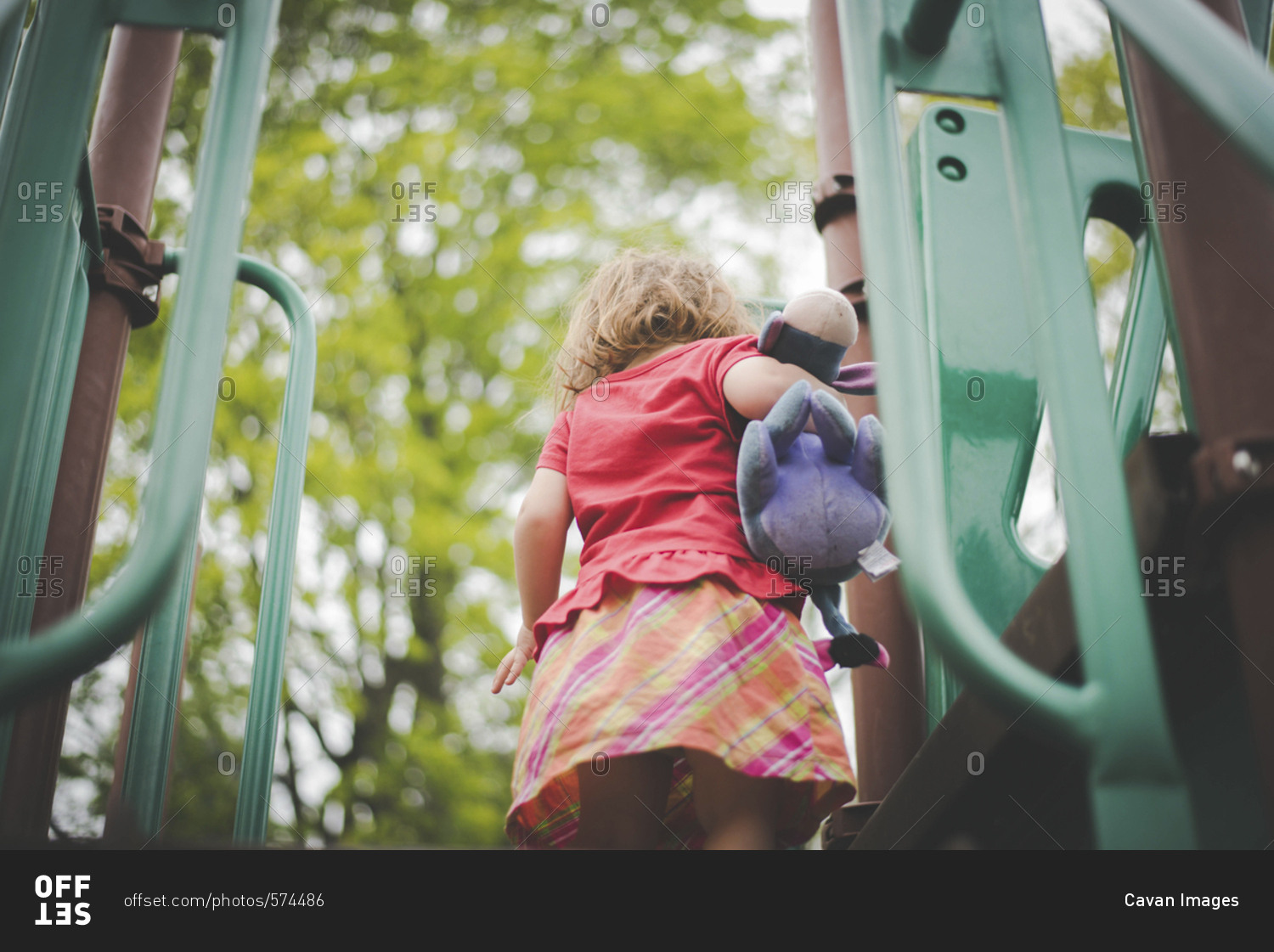 Low angle view of girl with stuffed toy standing on outdoor play equipment