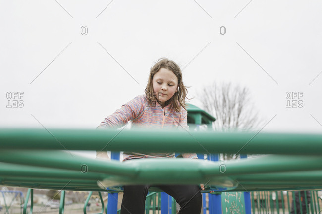 Low angle view of girl climbing on jungle gym against clear sky at playground