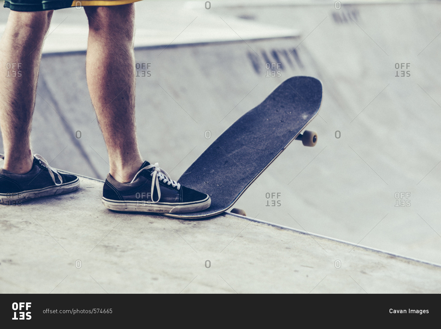 Low section of young man with skateboard at the edge of sports ramp