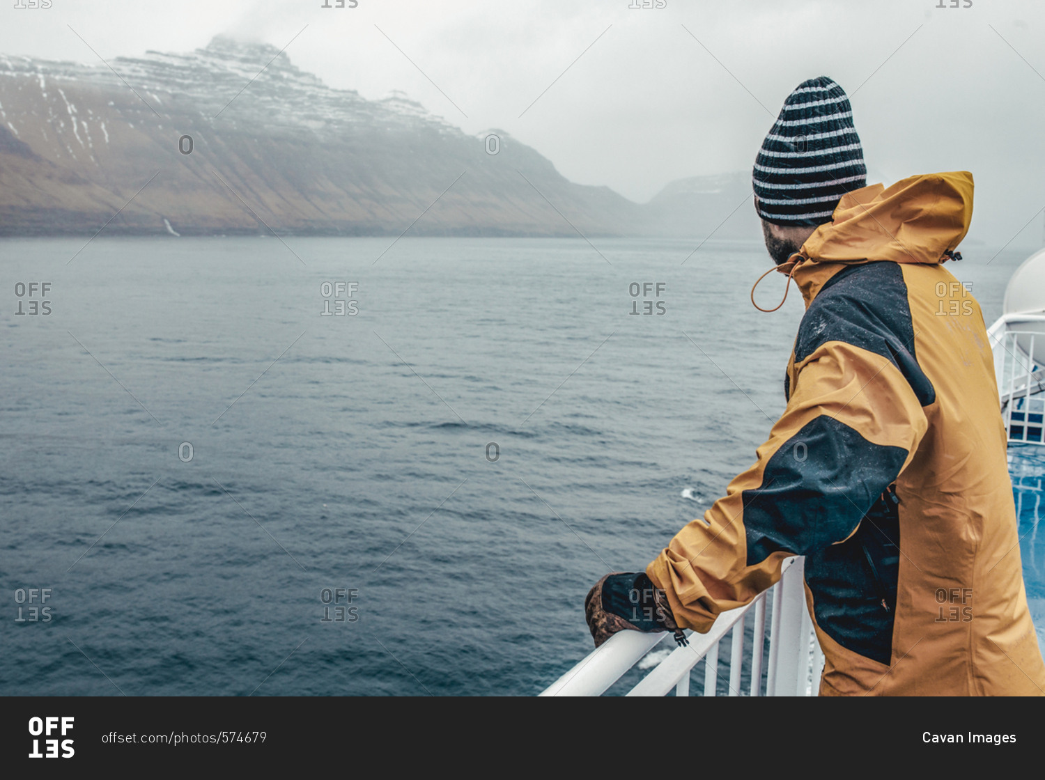 Side view of man looking at view while standing by railing on boat during rainy season