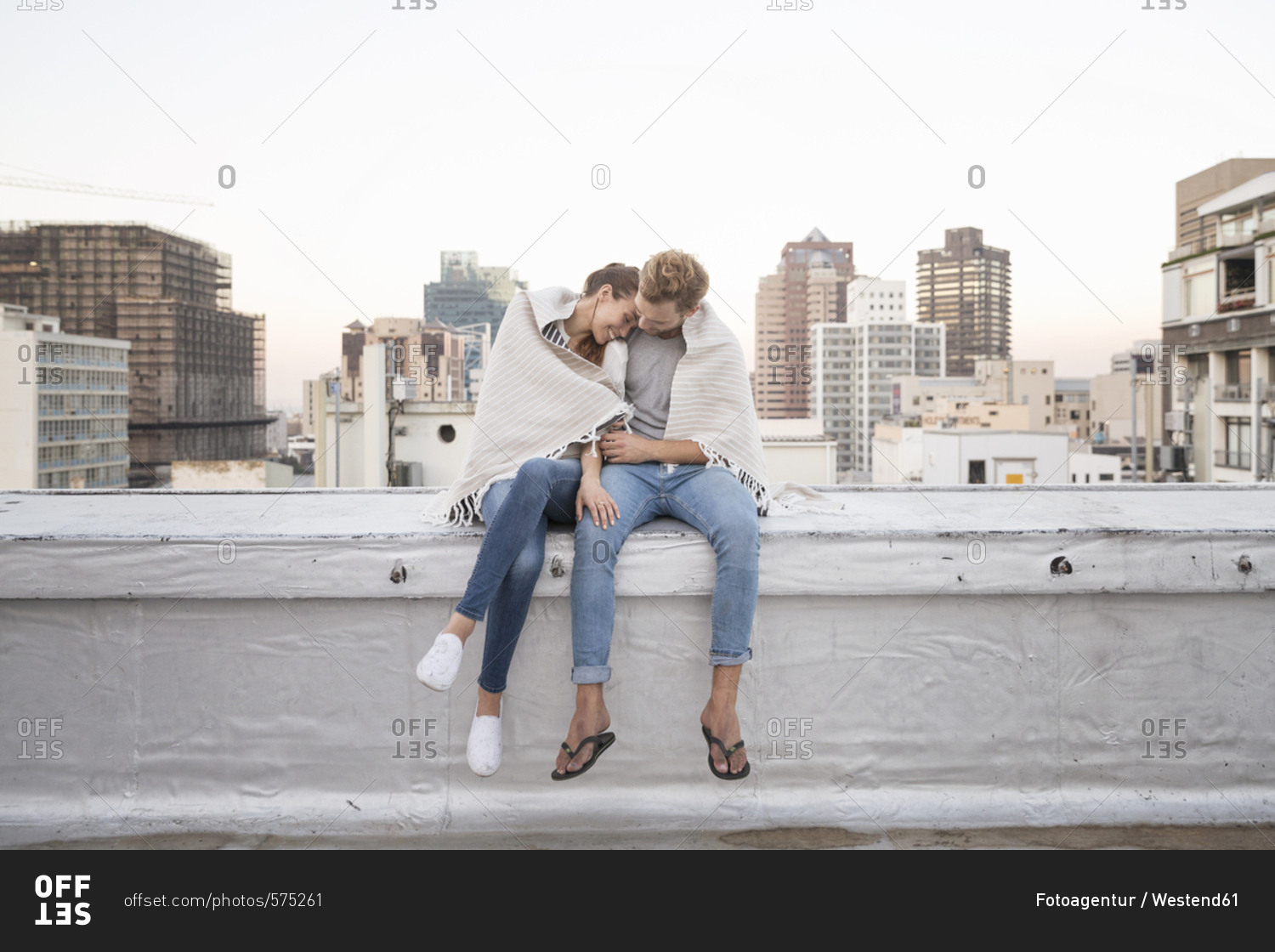Romantic couple sitting on rooftop terrace enjoying the view stock