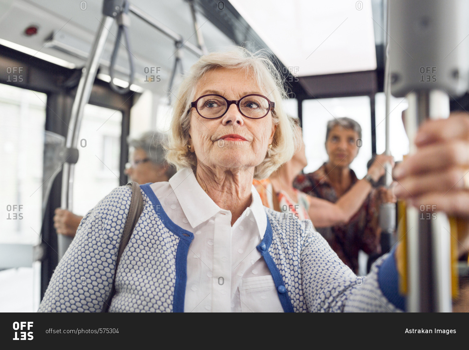 Senior woman holding handrail in bus
