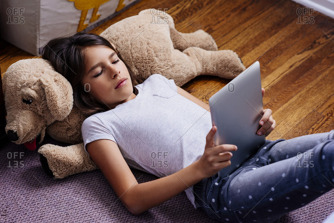 High angle view of girl using digital tablet while lying on rug in bedroom