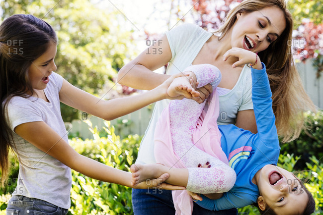 Cheerful mother and daughter picking girl upside down at yard