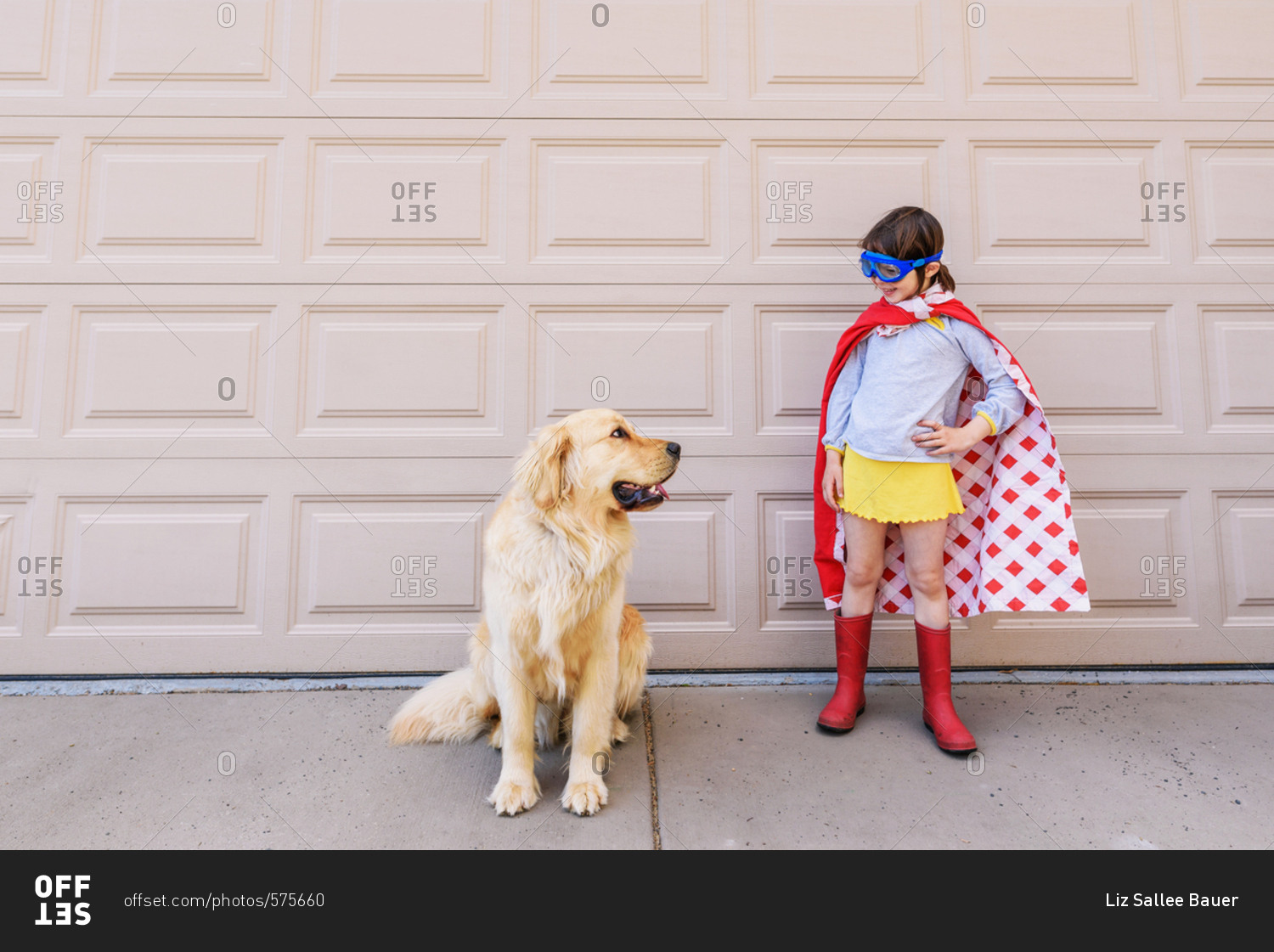 Young girl in super hero cape outside with dog