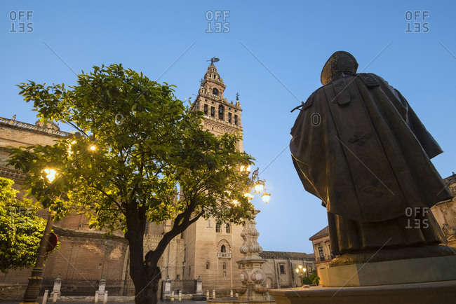 Spain, Seville, Plaza Virgin De Los Reyes, Statue and Giralda Tower at dusk